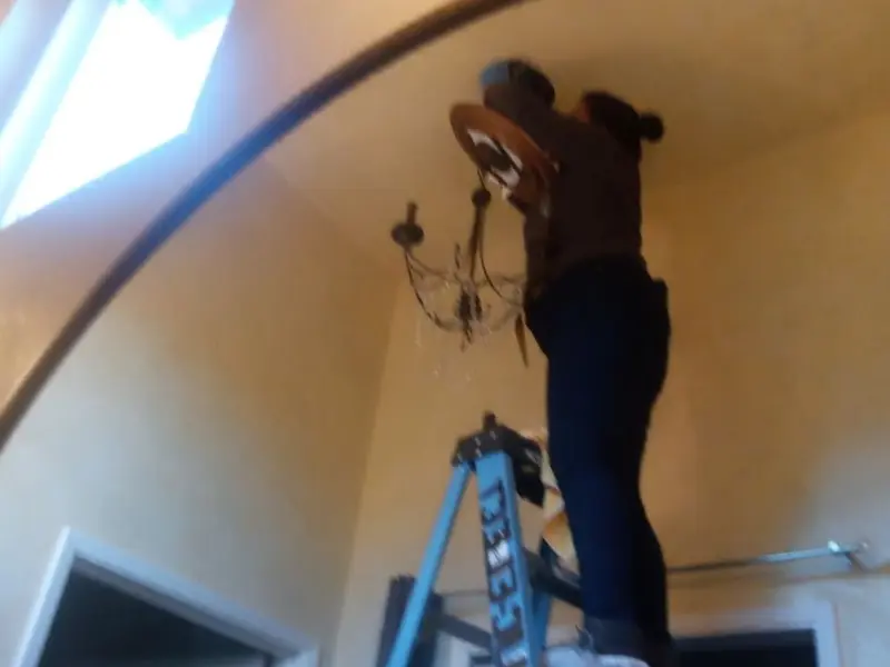 Electrician installing a chandelier in a Bret Harte residence